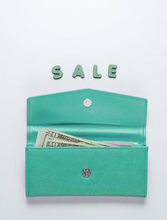 Blue trendy wallet on white background with word sale. Top view. Minimal concept