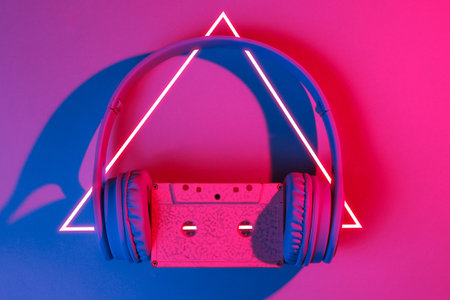 Headphones with audio cassette. 80's synth wave and retrowave glowing triangle futuristic aesthetics. Old fashioned abstraction conceptの写真素材