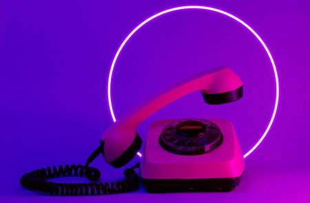 Old style rotary telephone with soaring telephone handle. 80's synth wave and retrowave glowing circle futuristic aesthetics. Old fashioned abstraction conceptの写真素材