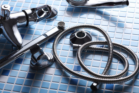 Parts of disassembled bathtub faucet with shower on tile backgroundの写真素材