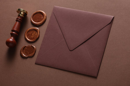 Envelope with wax seals and vintage stamp on brown background. DIY, Gift certificate, wedding invitation. Top viewの写真素材