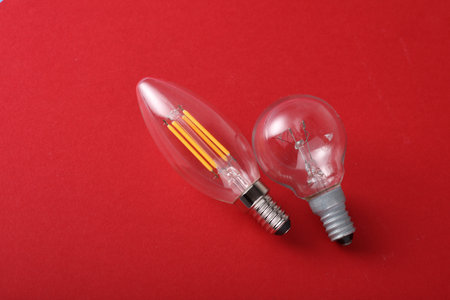 Incandescent and Energy Saving Filament Light Bulbs on red Background