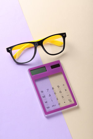 Calculator with eyeglasses on a pastel background. Business conceptの写真素材