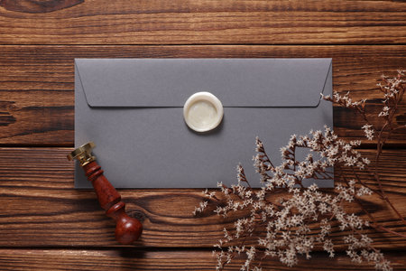 Envelope with wax seal and vintage stamp, dry flowers on wooden background. Gift certificate, wedding invitation. Flat layの写真素材