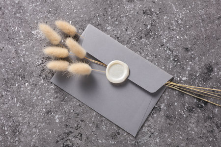 Envelope with wax seal and dry lagurus flowers on dark gray concrete background. Gift certificate,...