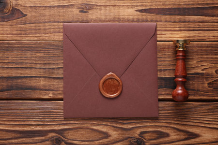 Envelope with wax seal and vintage stamp on wooden background. Gift certificate, wedding invitation