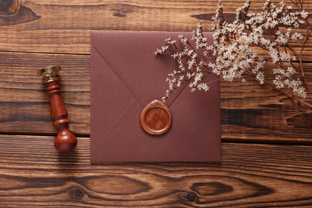 Envelope with wax seal and vintage stamp, dry flowers on wooden background. Gift certificate, wedding invitationの写真素材