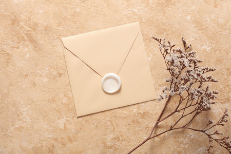 Envelope with wax seal and dry flowers on beige concrete background. Gift certificate, wedding invitation.の写真素材