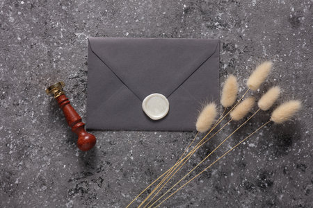 Envelope with wax seal and vintage stamp, dry lagurus flowers on concrete background. Gift...