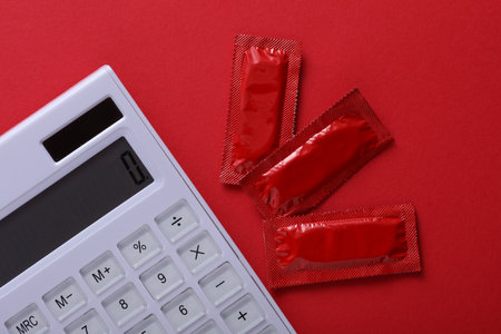 Calculator and Condom packages on a red backgroundの写真素材