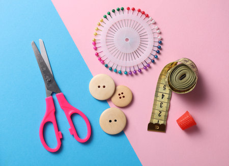 Tailor sewing accessories on pink blue background.