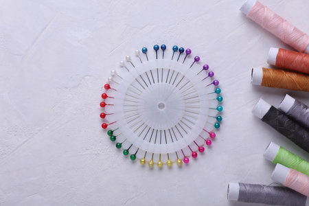 Set of sewing pins, skeins of thread on gray concrete background