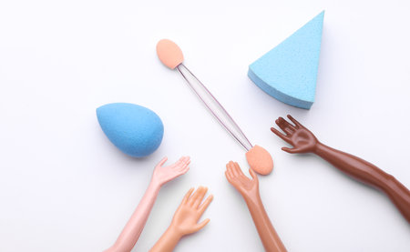 Doll's hands holding makeup accessories on white backgroundの写真素材