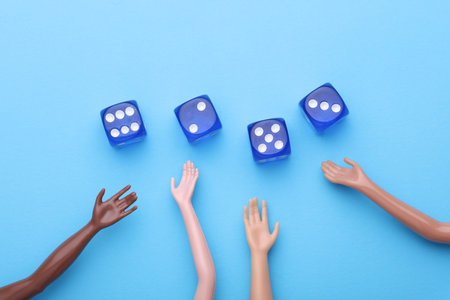 Hands of dolls and dice on blue background