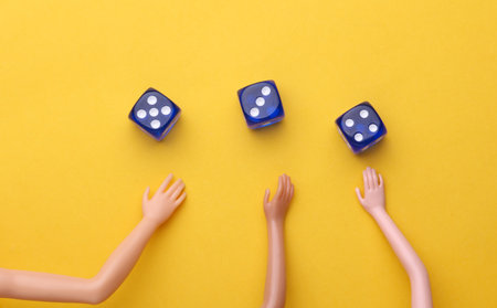 Hands of a dolls and dice on yellow backgroundの写真素材