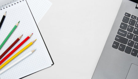 Back to school minimalistic concept. Laptop, color pencils, notebook on white background.の写真素材