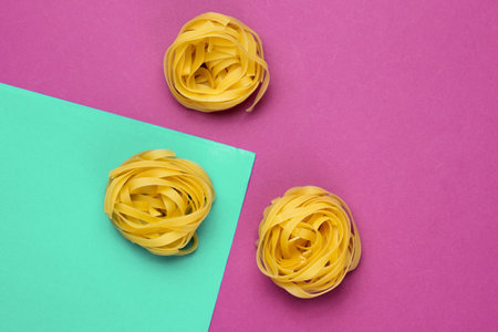 Minimalism italian food concept. Raw tagliatelle noodles on a blue-purple backgroundの写真素材
