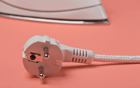 Iron with electric plug on vanilla background close upの写真素材