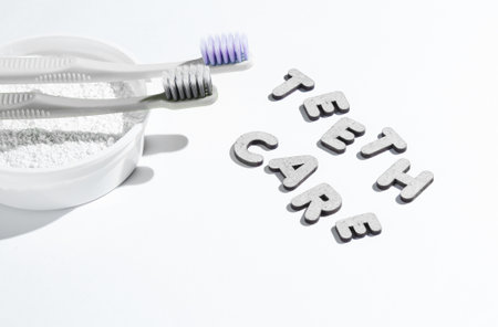 Two toothbrushes, tooth powder on white background with slogan teeth care. Minimalism oral hygiene concept.の写真素材