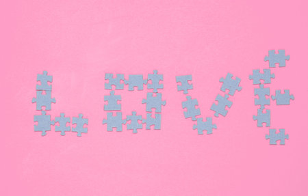 Particles puzzle in the shape of the word love on pink background