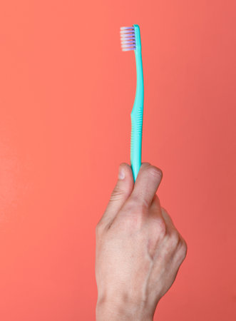 Toothbrush in hand on pink backgroundの写真素材