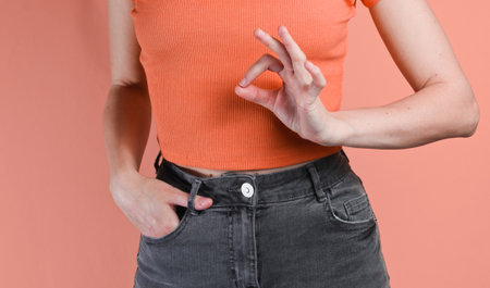 Woman shows a gesture okay on pink background. Crop photo, studio shotの写真素材