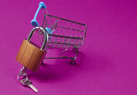 Minimalistic shopping concept. Mini shopping trolley with a lock on pink background.の写真素材