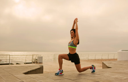 Young fit woman in sportswear doing yoga exercises at sunrise on the beach
