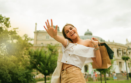 Emotional beautiful shopaholic woman with paper shopping bags posing at camera outdoorsの写真素材