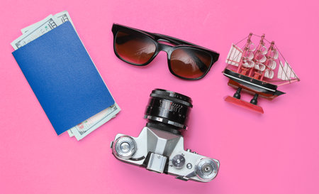 Traveler accessories, retro camera on pink background. Trip on the beach, vacation. Summer minimalistic background. Flat lay tourism allegory. Top viewの写真素材
