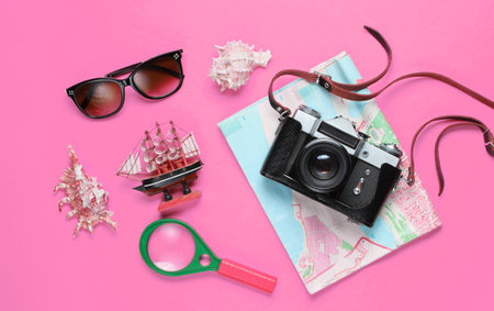 Traveler accessories, retro camera on pink background. Trip on the beach, vacation. Summer minimalistic background. Flat lay tourism allegory. Top viewの写真素材