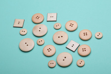 Wooden buttons on mint green background close up