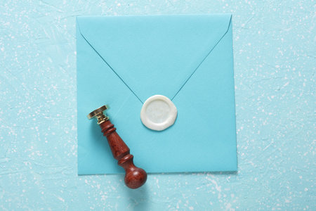 Envelope with wax seal and vintage stamp on blue concrete background. Gift certificate, wedding invitationの写真素材