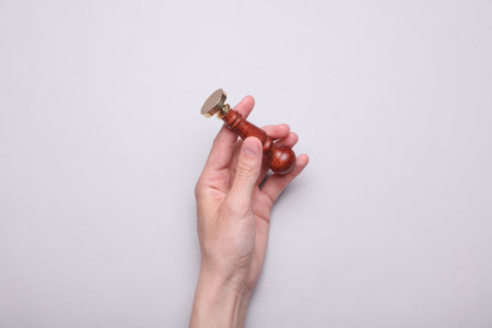 Female hand holding vintage personal stamp on gray backgroundの写真素材