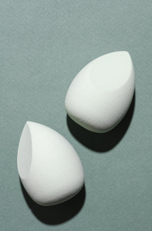 Eggs makeup sponges. Blenders for foundation on green background with shadow. Creative layout....