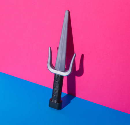 Toy plastic sai weapons on pink blue background
