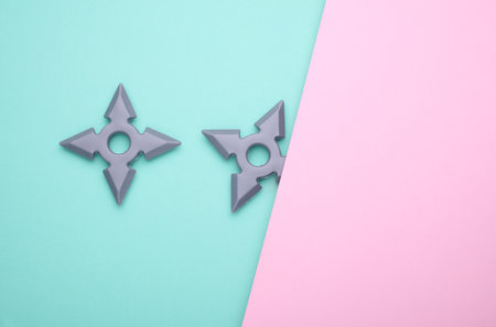 Toy plastic ninja shurikens on blue pink background