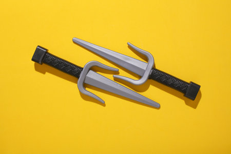 Toy plastic sai weapons on yellow backgroundの写真素材