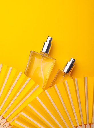Creative top view showcase perfume bottle with fan on yellow background. Beauty conceptの写真素材
