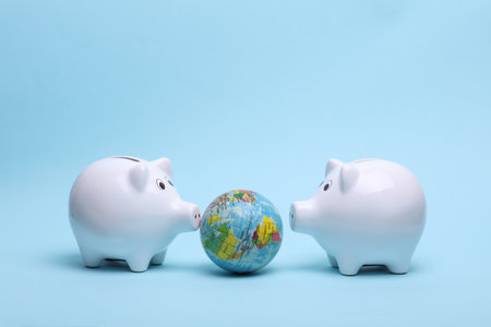 Ceramic white piggy bank with globe on a blue background. Business concept. Conceptual photo