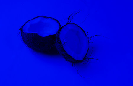 Two halves of chopped coconut in blue neon lightの写真素材