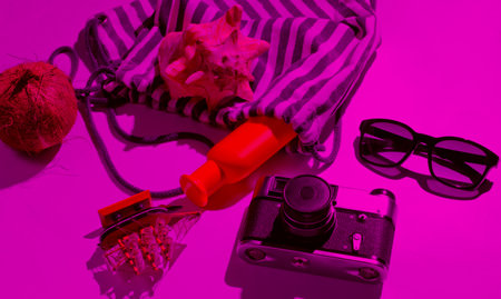 Creative vacation on sea Still life. Beach accessories in pink neon light with shadowsの写真素材