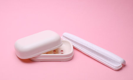 Plastic case for storing toothbrush and soap dish on pink backgroundの写真素材