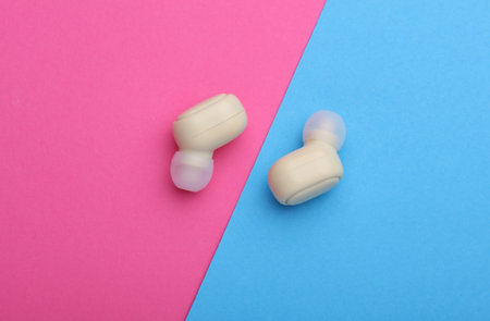 Wireless earbuds on a pink blue background