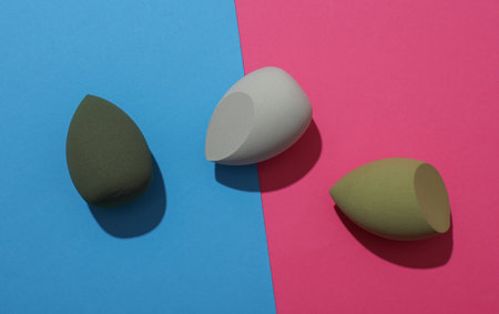 Eggs makeup sponges for foundation on pink blue background