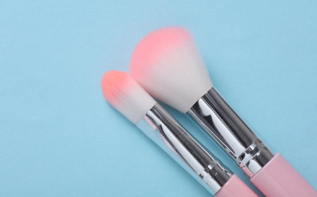 Set of pink makeup brushes on a blue background