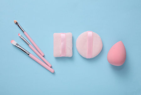Makeup sponges and brushes on a blue background