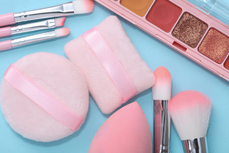 Makeup brushes with eye shadow palette, sponges on blue background. Flat layの写真素材