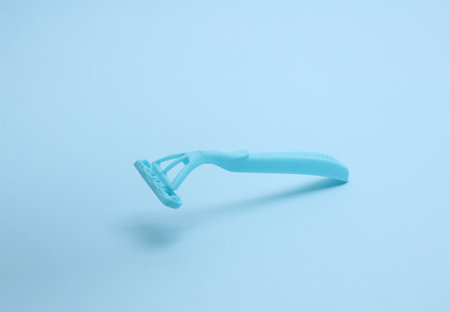 Blue disposable razor floating on blue background