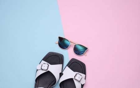 Women's leather sandals with sunglasses on pink blue background. Summer shoes and accessories. Top viewの写真素材